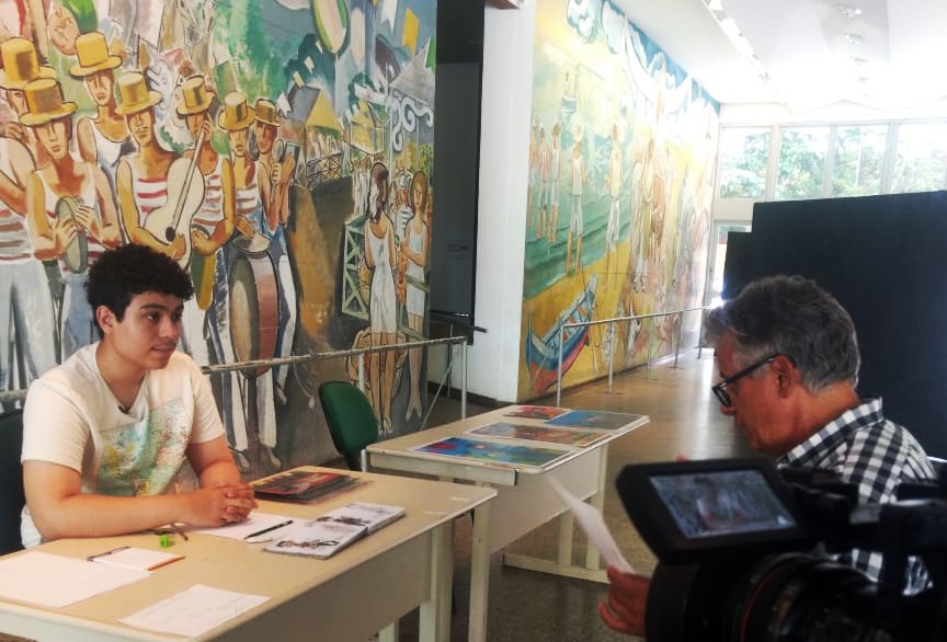 Aluno Thiago Santos concede entrevista para cineasta no local da exposição 
