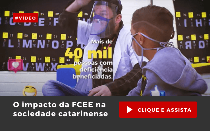 Imagem de duas pessoas, com máscaras transparentes, alfabeto ao fundo, gestos com mãos e o texto: O impacto da FCEE na sociedade catarinense – clique e assista. 