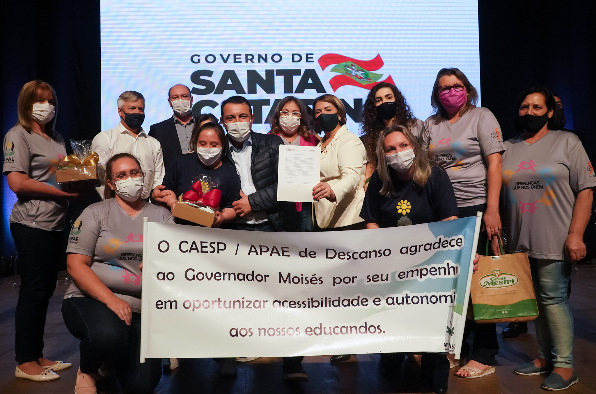 Quinze pessoas posam para foto, ambiente interno, faixa de agradecimento ao governador