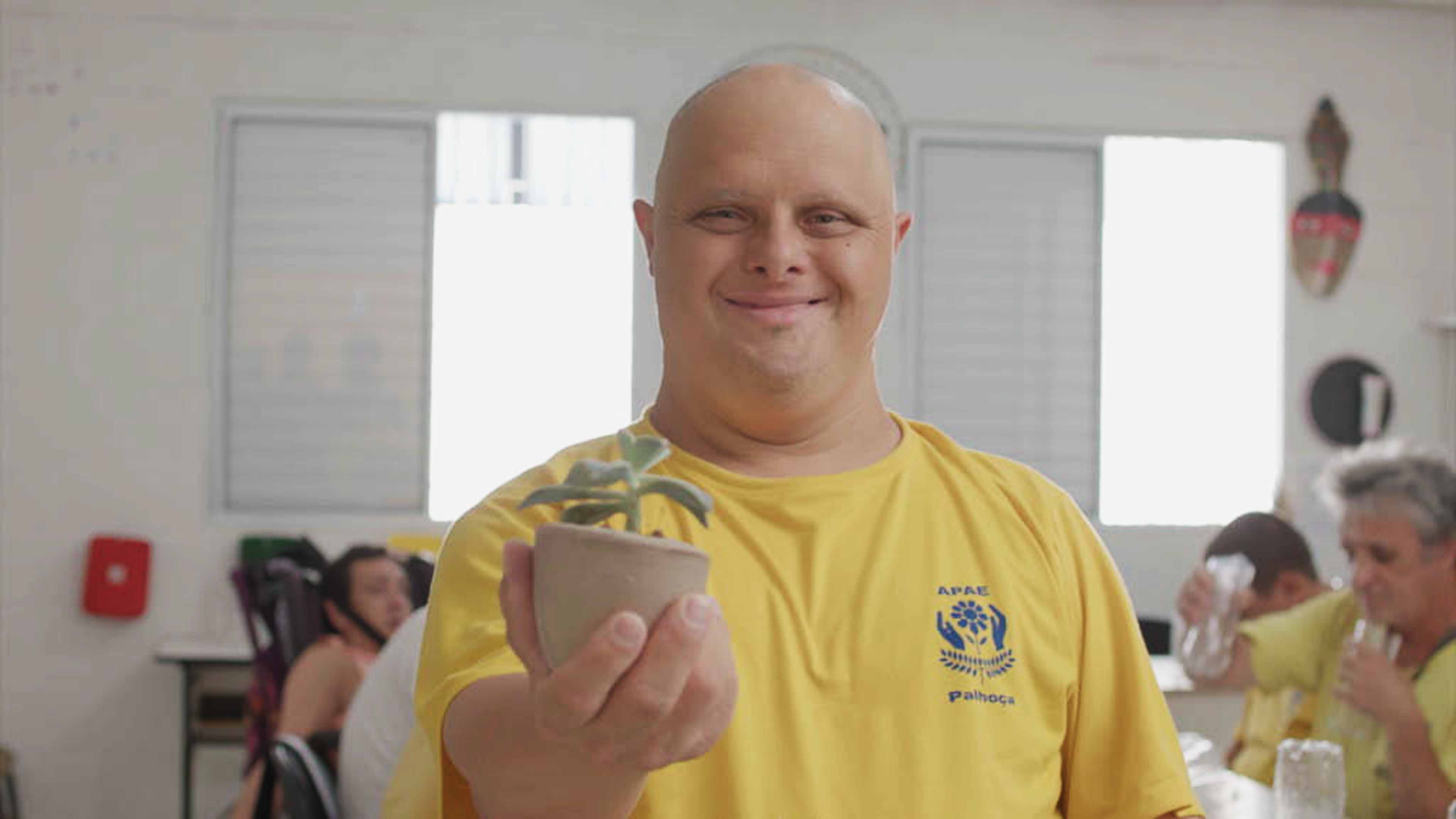 Menino com camiseta amarela, calvo, sorri para câmera. 