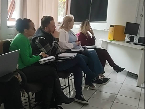 quatro pessoas sentadas olham para frente em sala de aula