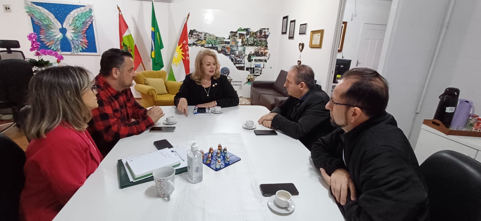 sete pessoas sentadas em volta de mesa de reunião, ambiente interno