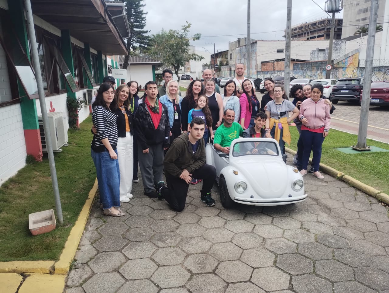 15 pessoas ao lado de fusca em miniatura, ambiente externo, rua