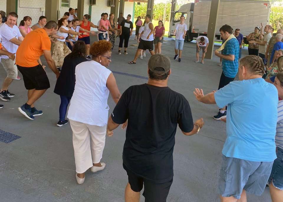 dezenas de pessoas em pé em roda com as mãos para cima