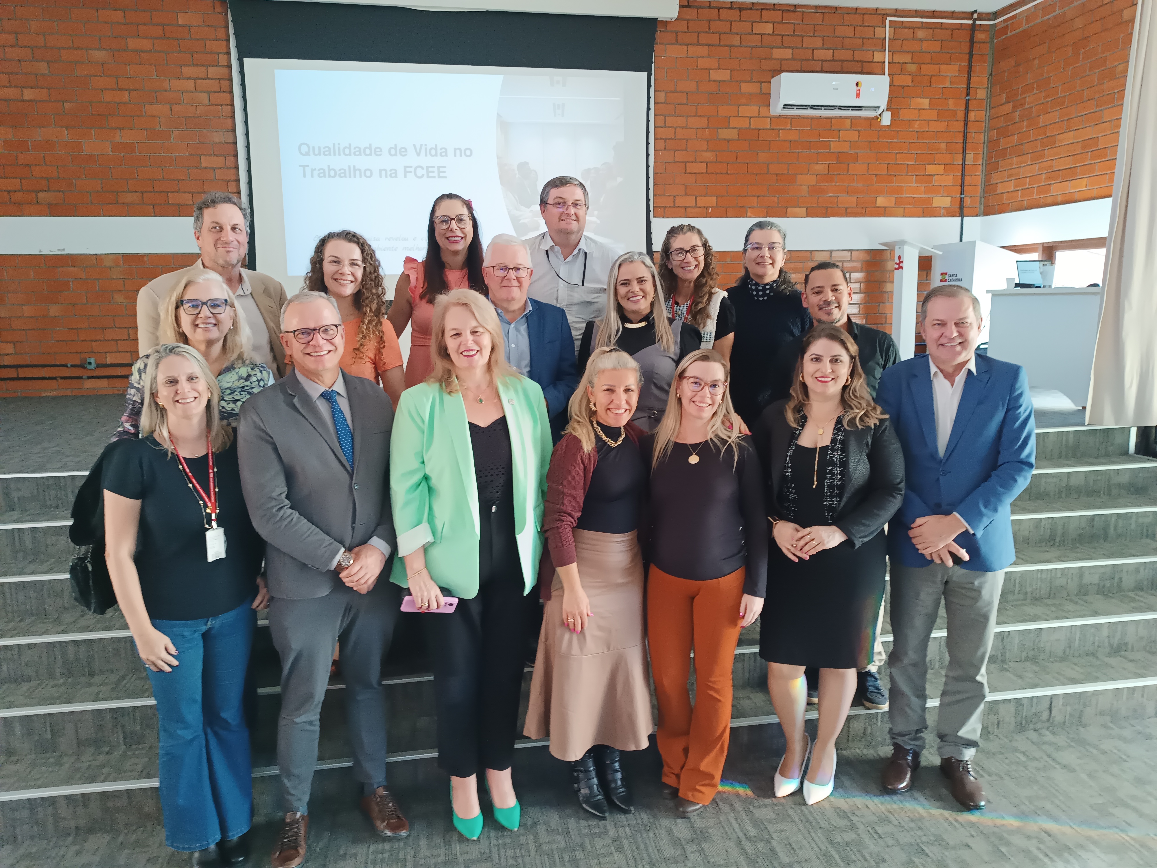 Turma do Mestrado com professores da UFSC 15 pessoas em pé posam para foto em frente ao palco do auditório