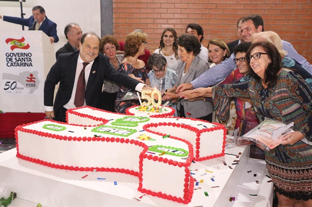 Homenageados no evento cortam o bolo fictício dos 50 anos